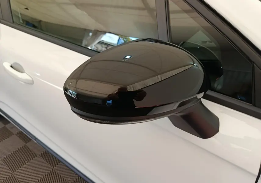 Rétroviseur noir en gros plan côté conducteur d'une Renault Clio blanche 2024, avec porte et vitre partiellement visibles.