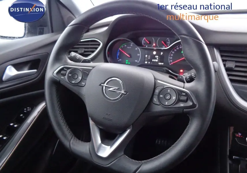 Vue rapprochée du volant noir de l’Opel Grandland X hybride, avec tableau de bord et commandes visibles.