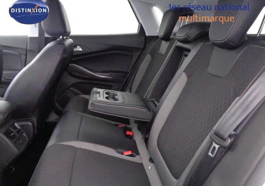 Vue intérieure côté droit des sièges arrière noirs et gris avec accoudoir central déployé de l’Opel Grandland X hybride rechargeable.
