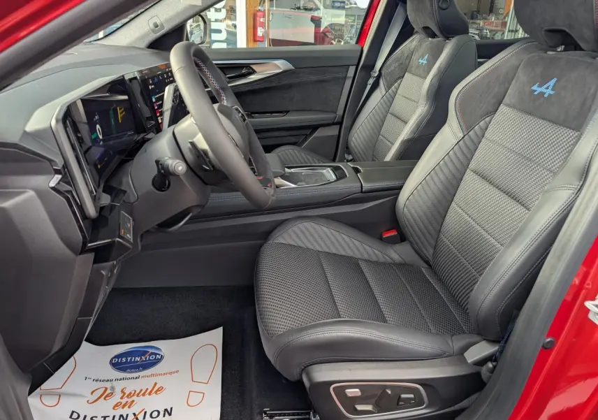 Vue intérieure côté conducteur du Renault Austral rouge, sièges en tissu carbone Alcantara avec logo Alpine bleu brodé.