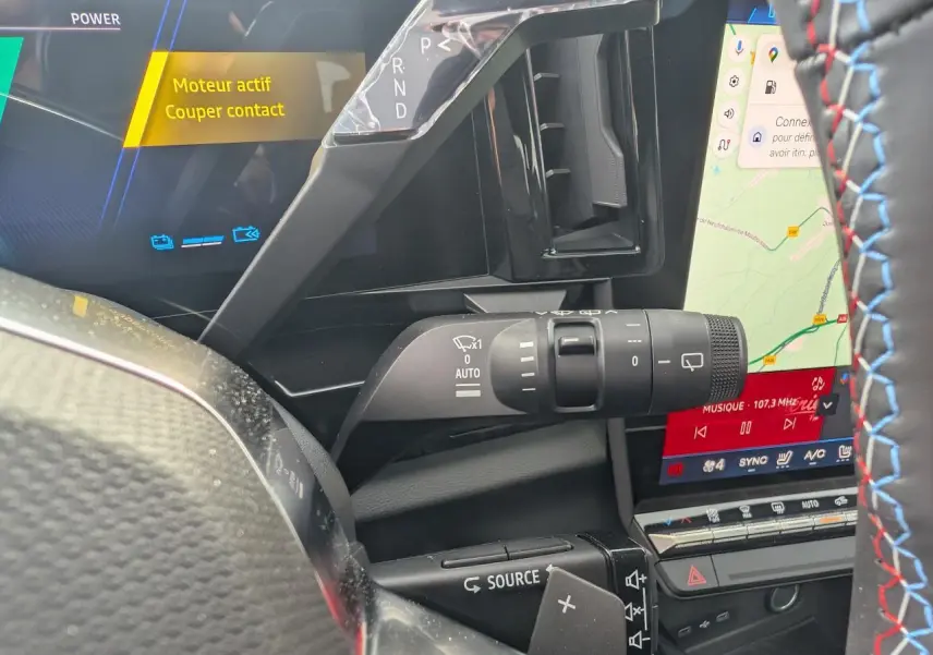 Gros plan sur la commande d'essuie-glace et le volant avec surpiqûres tricolores du Renault Austral rouge métallisé 2025.