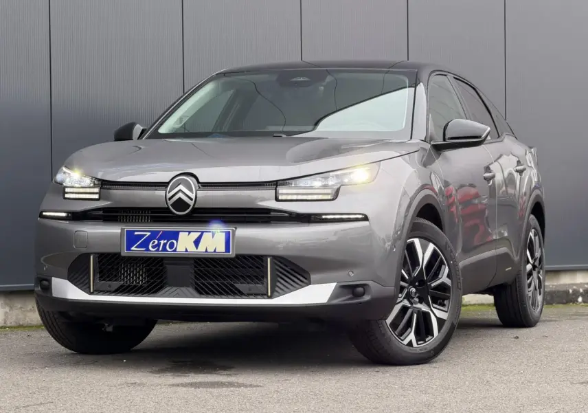 Citroën C4 2025 gris Mercury avec toit noir, vue 3/4 avant mettant en valeur les phares LED et jantes alliage.