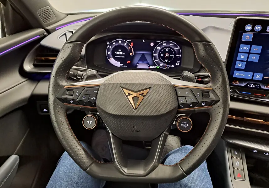 Vue intérieure centrée sur le volant perforé du CUPRA TERRAMAR 2025 avec tableau de bord numérique et commandes intégrées.