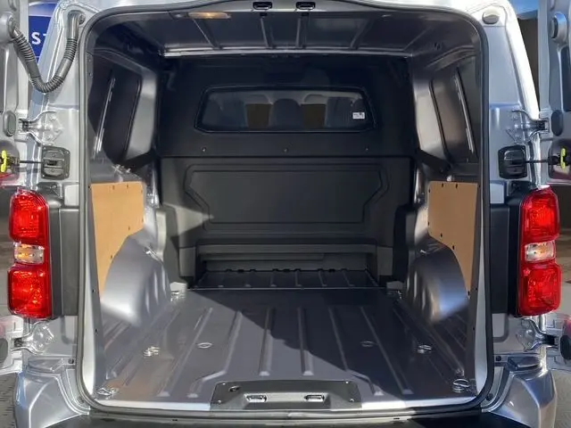 Vue arrière du Peugeot Expert XL gris acier, montrant l’espace de chargement vide avec cloison et parois latérales.