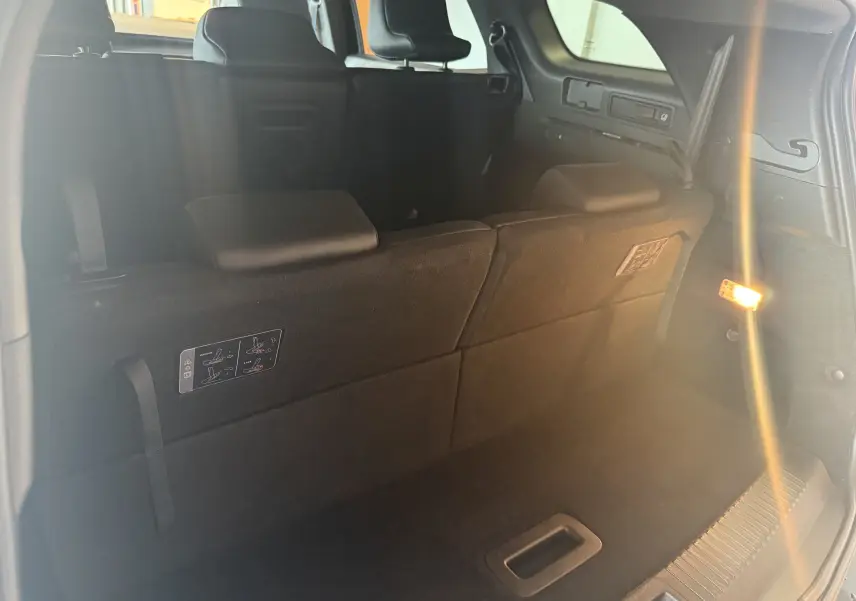 Coffre ouvert vu de l’arrière d’un Renault Espace VI noir, montrant la banquette arrière et l’éclairage intérieur.