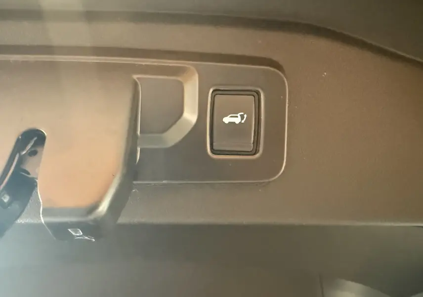 Bouton d'ouverture électrique du hayon visible en gros plan à l'intérieur du coffre du Renault Espace VI noir.