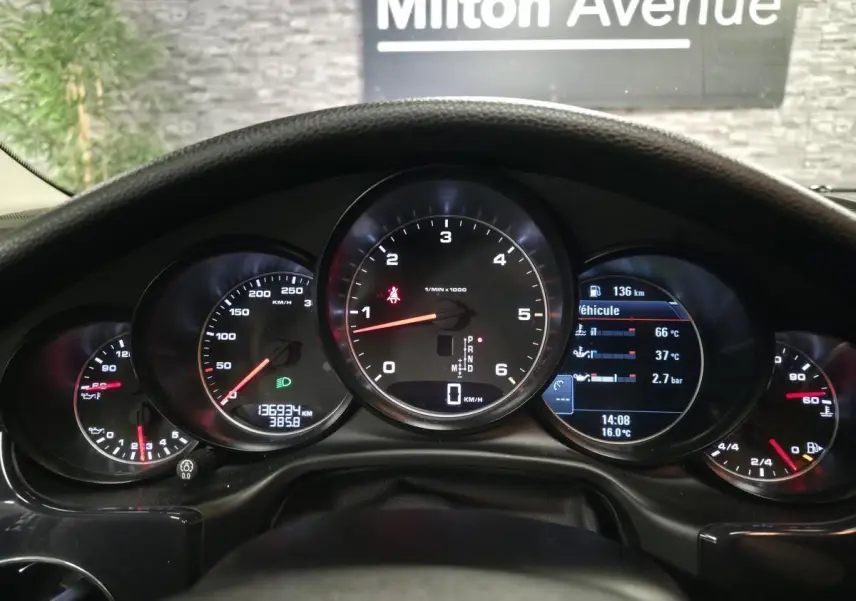 Vue rapprochée du tableau de bord noir de la Porsche Panamera marron, affichant les compteurs ronds et numériques.