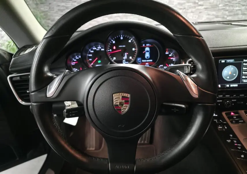 Vue intérieure centrée sur le volant cuir noir de la Porsche Panamera 2011 avec tableau de bord et instruments ronds éclairés.