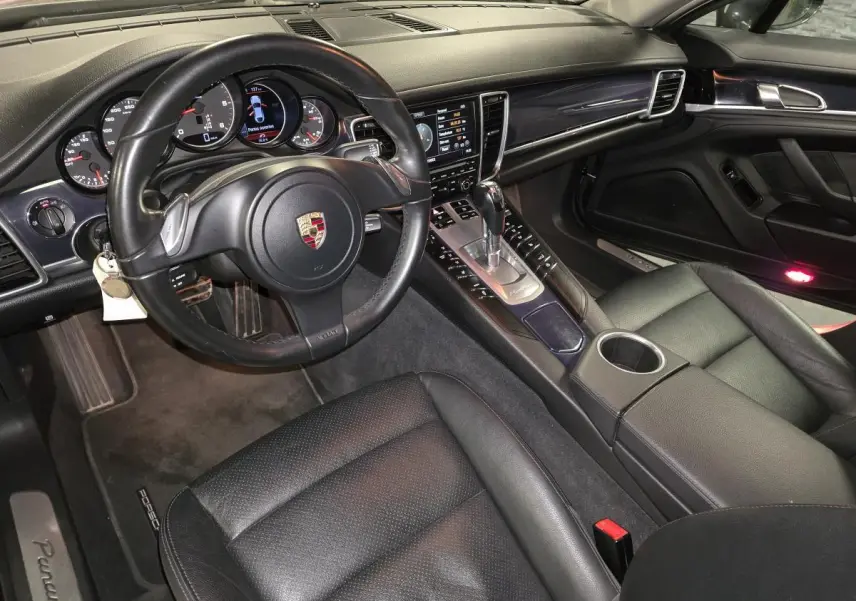 Vue intérieure côté conducteur de la Porsche Panamera 2011, cuir noir, console centrale avec levier de vitesse Tiptronic.