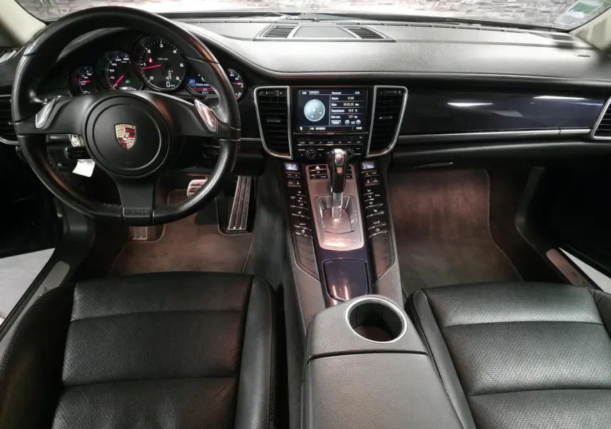 Intérieur avant noir d’une Porsche Panamera 2011, vue centrale sur le tableau de bord et la console avec levier de vitesse.
