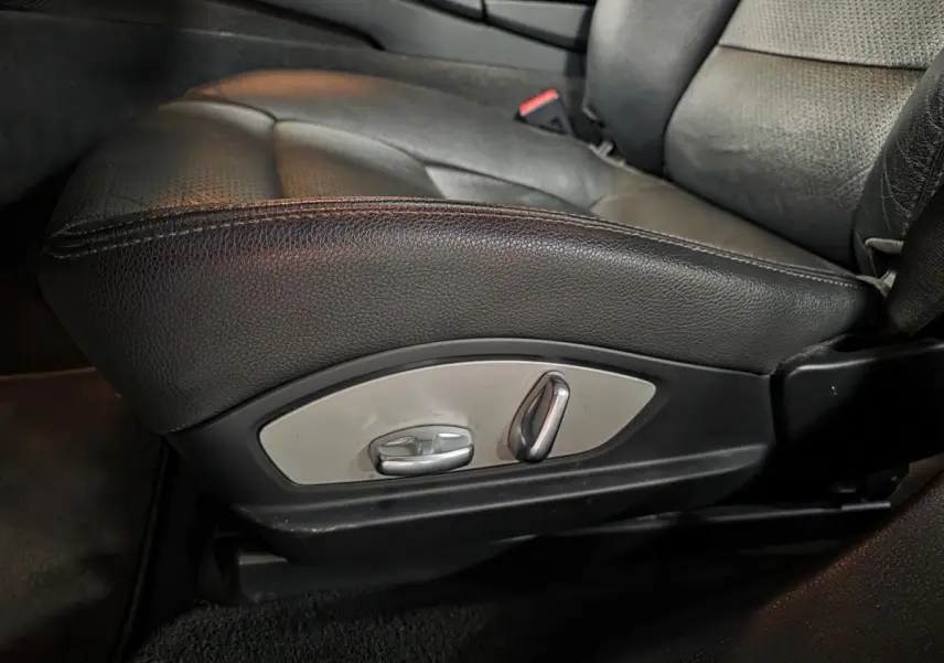 Gros plan sur le siège avant gauche en cuir noir avec commandes électriques de réglage sur une Porsche Panamera marron.