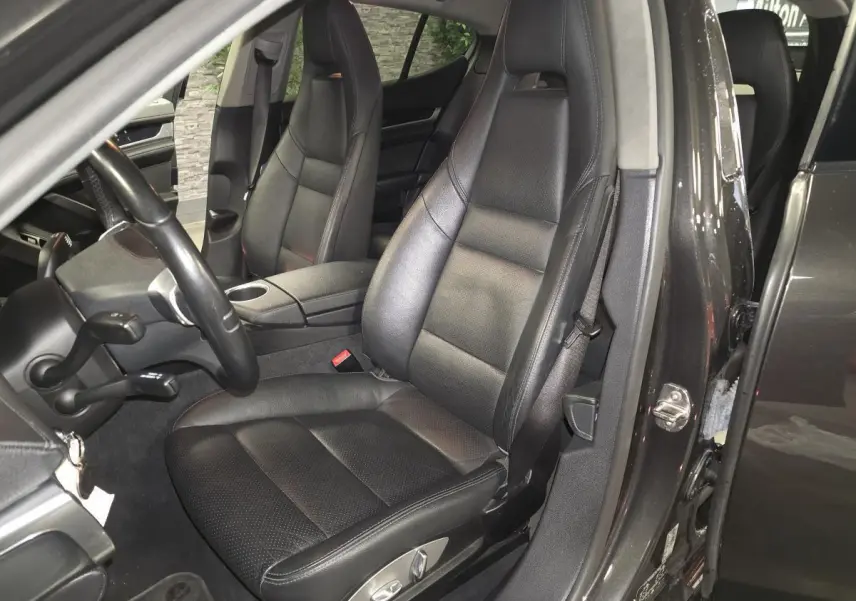 Vue intérieure côté conducteur de la Porsche Panamera marron, sièges cuir noir et volant sport à 3 branches.