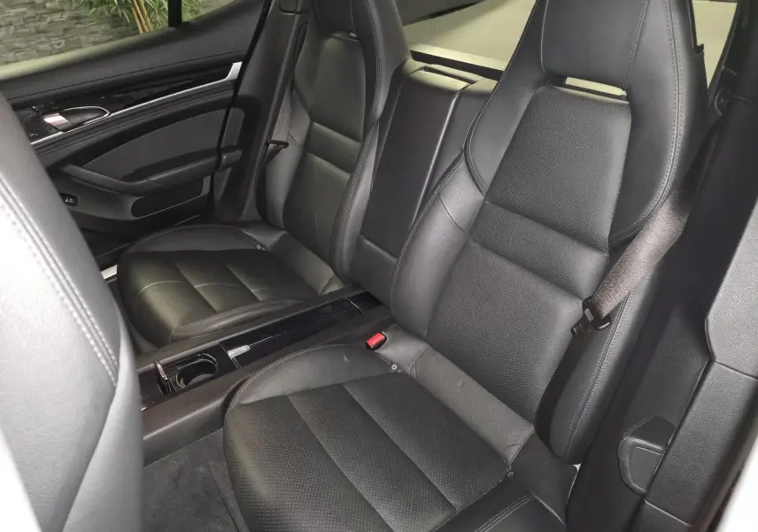 Vue intérieure des sièges avant en cuir noir de la Porsche Panamera 3.0 V6 TDI, avec console centrale et porte-gobelet.