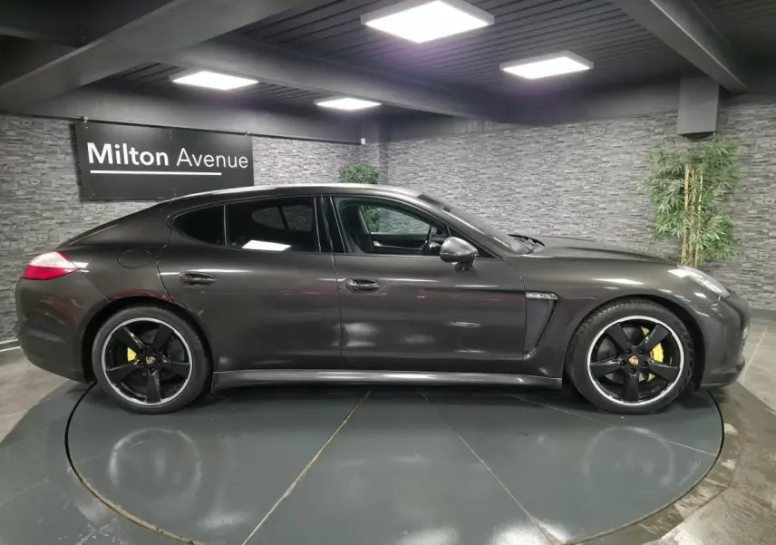 Vue latérale droite d'une Porsche Panamera marron métallisée avec jantes noires sport et étriers de frein jaunes.