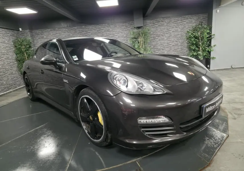 Porsche Panamera marron vue 3/4 avant droit, jantes noires sport 20 pouces et feux de jour à LED visibles.