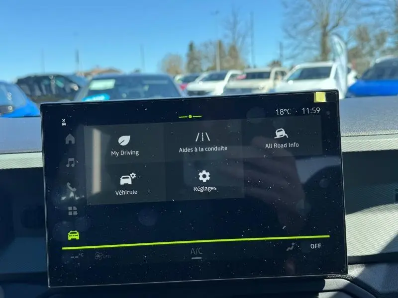 Écran tactile central du tableau de bord du Dacia Duster blanc, affichant les aides à la conduite.