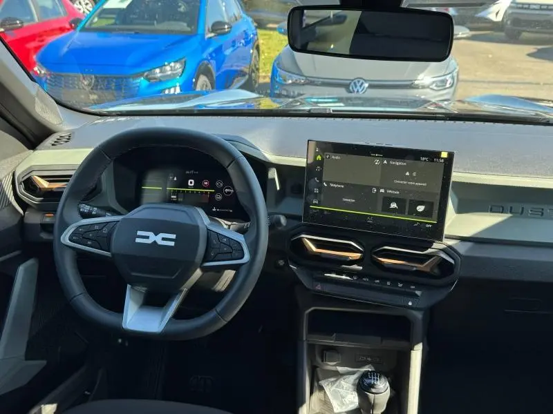 Vue intérieure du tableau de bord du Dacia Duster blanc 2025, avec volant multifonction et écran tactile central.
