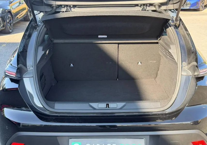 Coffre ouvert vu de l'arrière d'une Peugeot 308 e-308 noire Perla Nera, montrant l'espace de chargement vide.