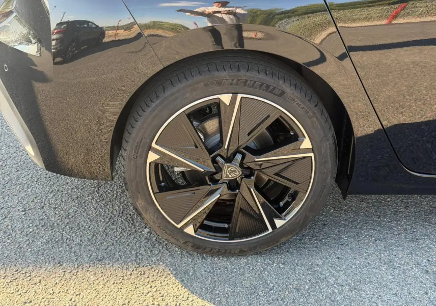 Gros plan sur la roue arrière droite de la Peugeot e-308 noire Perla Nera avec jante alu au design moderne.