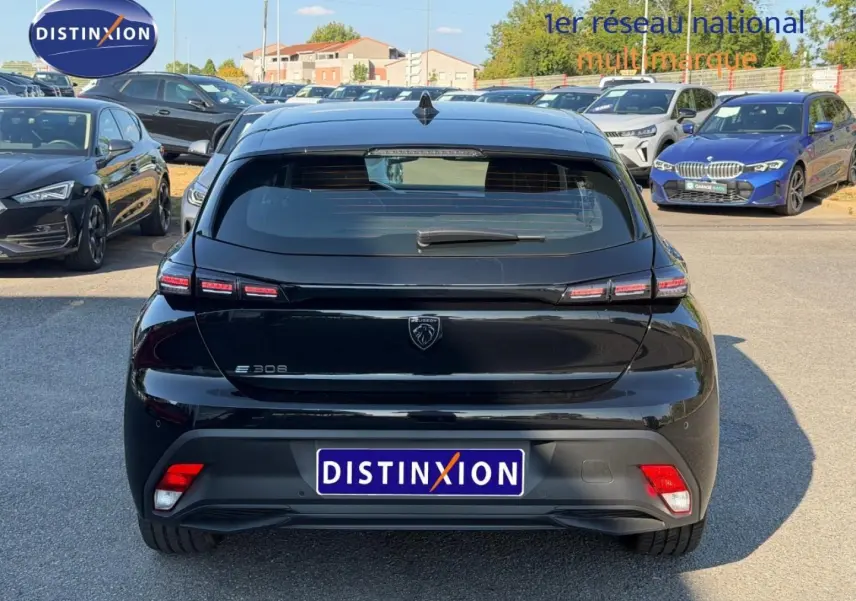 Vue arrière d'une Peugeot e-308 noire Perla Nera avec feux LED distinctifs et logo lion central.