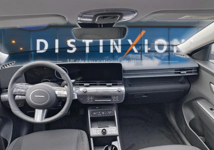 Vue intérieure avant du Hyundai Kona 2025 gris, montrant le volant cuir multifonction et l'écran tactile large.
