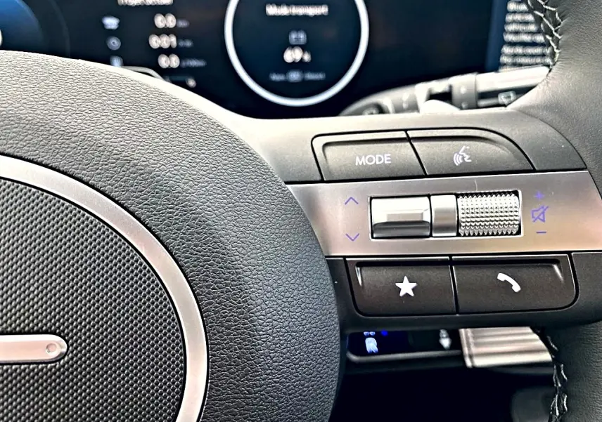 Gros plan sur le côté droit du volant cuir multifonction du Hyundai Kona gris, avec commandes audio et téléphone.