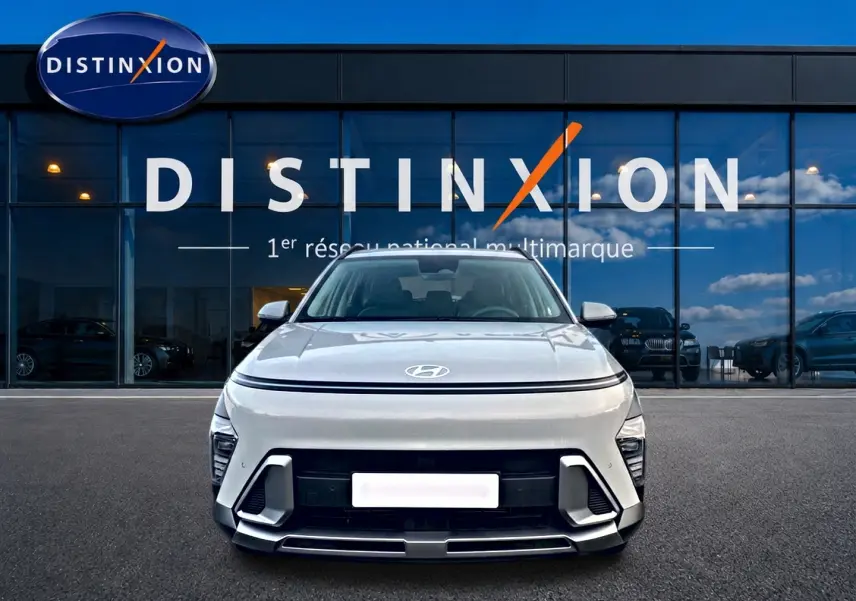 Vue de face du Hyundai Kona gris 2025 avec calandre minimaliste et feux LED fins, devant une vitrine Distinxion.