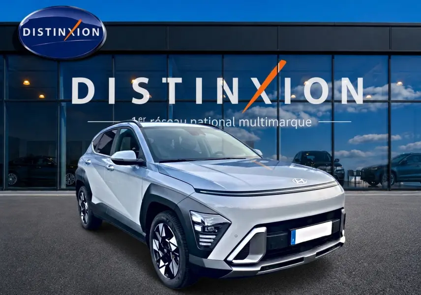 Hyundai Kona gris 2025 en 3/4 avant droit, avec jantes alliage et éclairage LED distinctif, devant vitrine Distinxion.