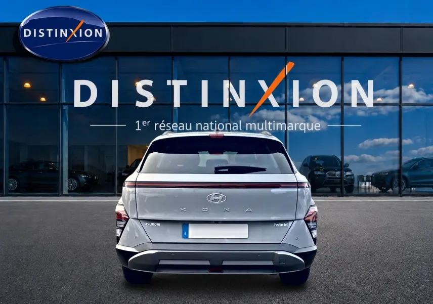 Vue arrière d'un Hyundai Kona gris 2025 avec bande lumineuse LED et logo Hyundai visible, devant une vitrine Distinxion.