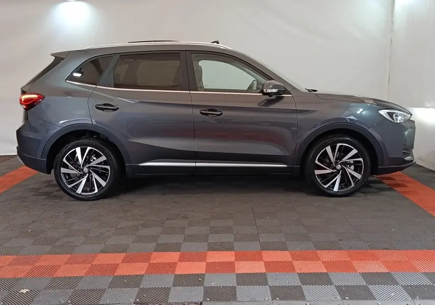Vue de profil côté gauche du MG Motor ZS gris foncé 2026 avec jantes alliage et feux arrière allumés.