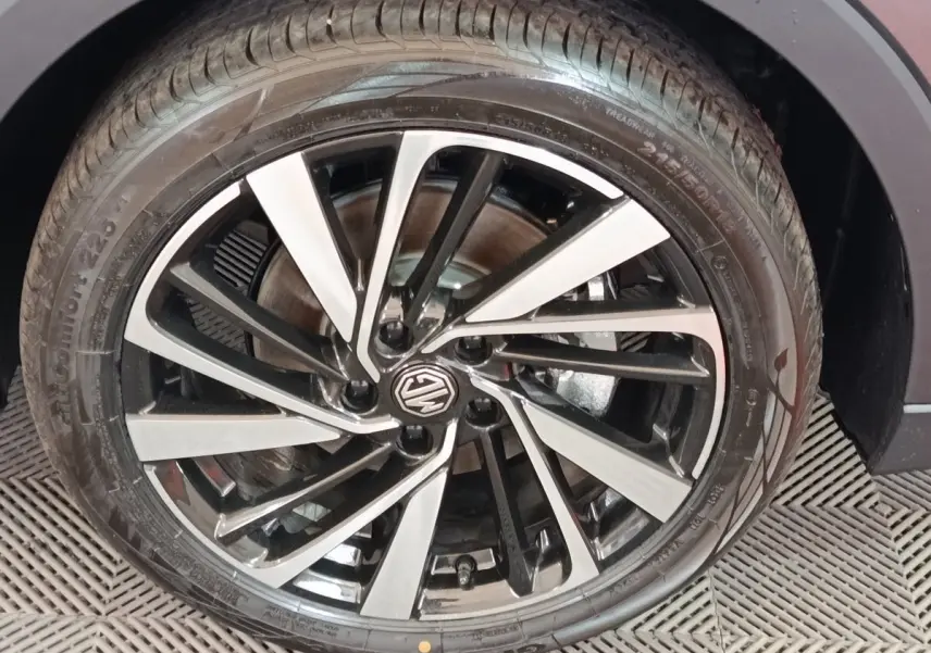 Gros plan sur la jante alliage bicolore noire et argent avec logo MG, montée sur pneu Continental d’un MG ZS gris foncé.