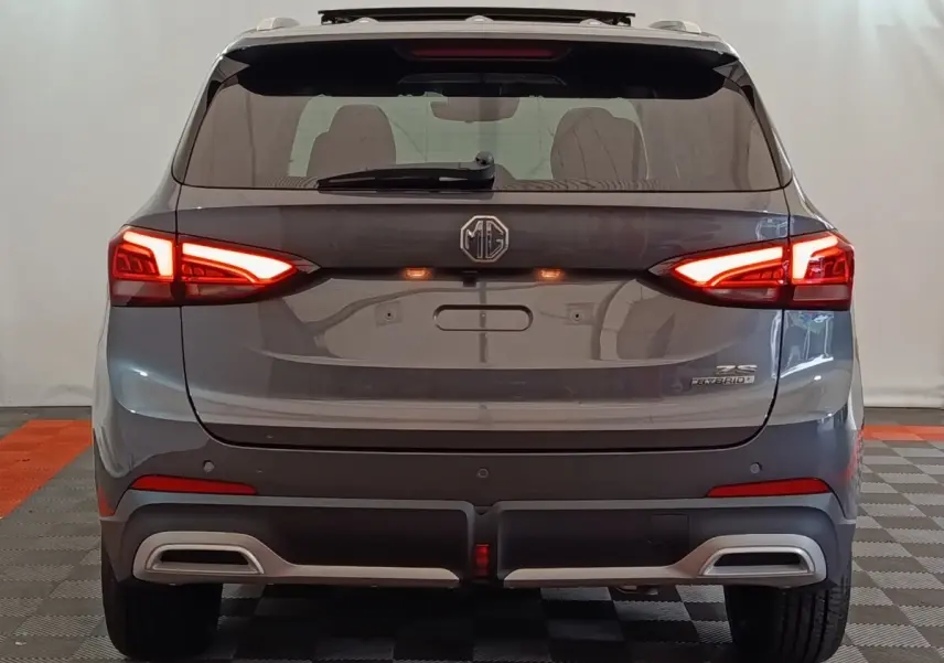 Vue arrière du SUV MG ZS gris foncé avec feux LED allumés et double sortie d’échappement intégrée au pare-chocs.