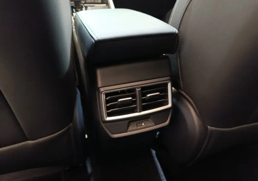 Vue rapprochée de l'accoudoir central arrière noir avec bouches d'aération et port USB du MG Motor ZS hybride 2026.