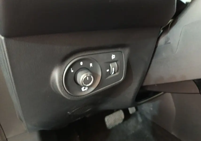 Gros plan sur les commandes de réglage des rétroviseurs intérieurs d’un MG Motor ZS gris foncé, côté conducteur.