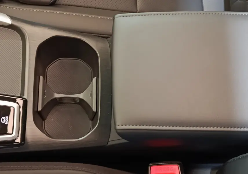Gros plan sur l'accoudoir central gris et porte-gobelets noirs du MG Motor ZS hybride 2026, intérieur moderne.