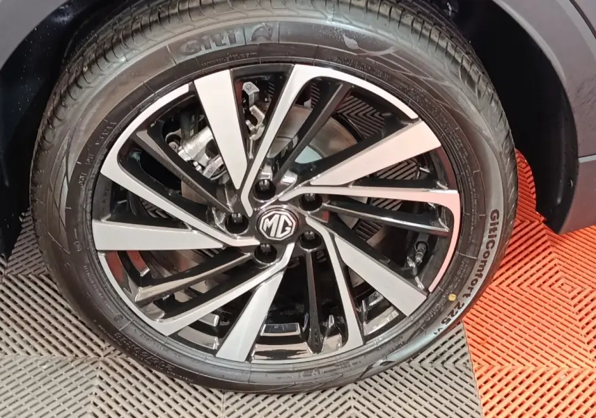 Gros plan sur la jante alliage bicolore noire et argentée du MG ZS gris foncé, avec logo MG au centre.