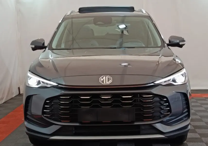 Vue frontale du MG ZS gris foncé 2026 avec phares LED allumés et calandre imposante noire.