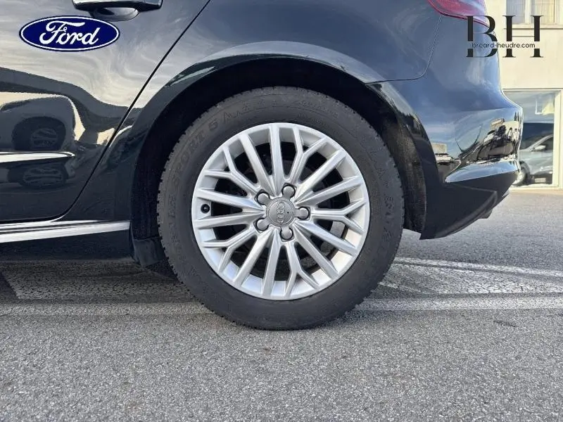 Gros plan sur la roue arrière droite d'une Audi A3 Sportback noire brillante avec jante alu multibranches.