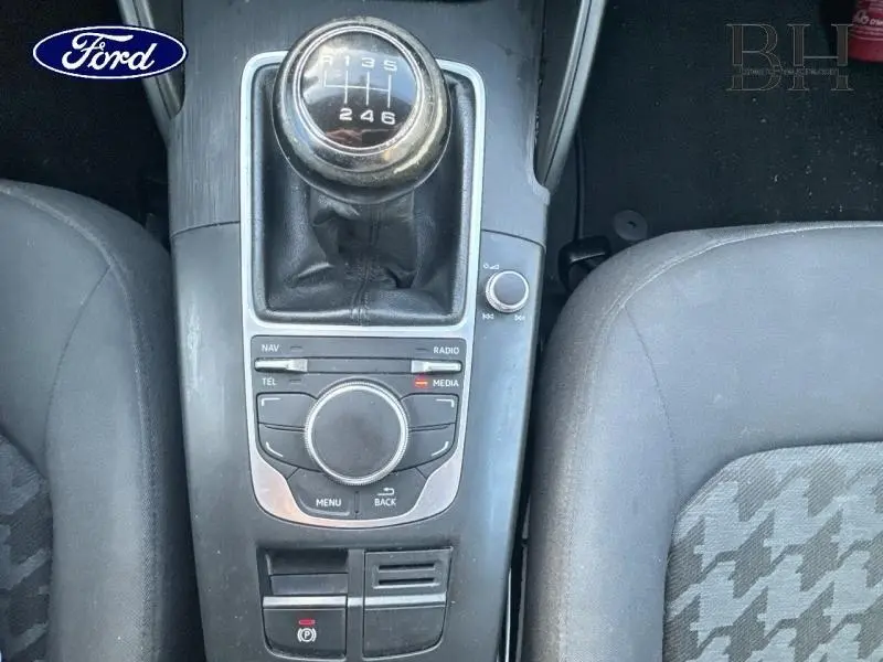 Gros plan sur la console centrale noire avec levier de vitesse manuel et commandes multimédia d'une Audi A3 Sportback 2016.