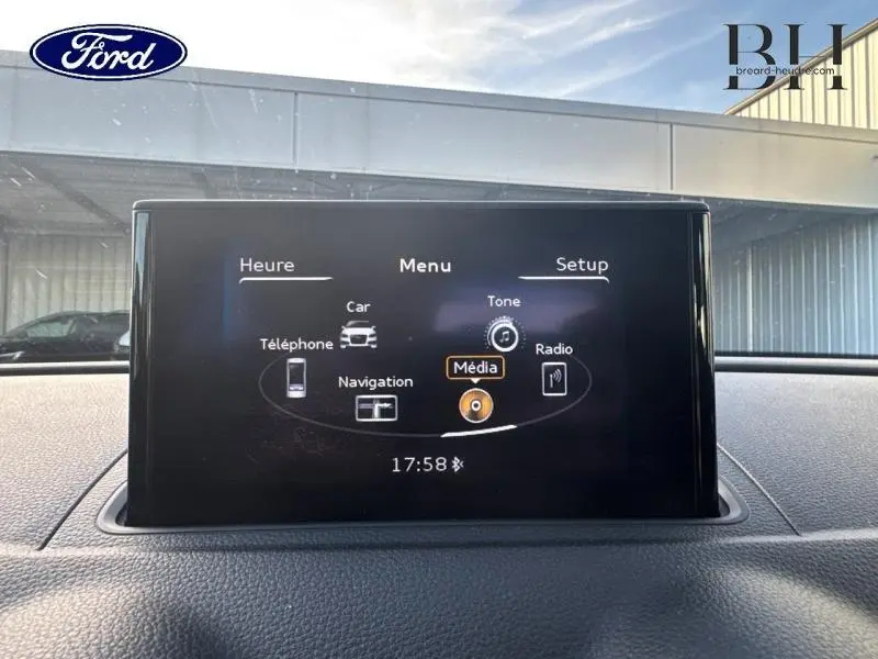 Écran multimédia en gros plan affichant le menu principal, dans l'habitacle d'une Audi A3 Sportback noire.