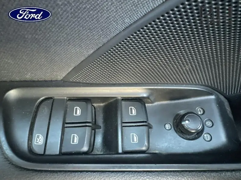 Gros plan sur les commandes de lève-vitres et réglage des rétroviseurs côté conducteur d'une Audi A3 Sportback noire.