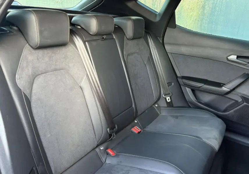 Vue côté droit des sièges arrière en suédine noir asphalte du CUPRA Formentor gris magnétique, avec ceintures et appuie-têtes visibles.