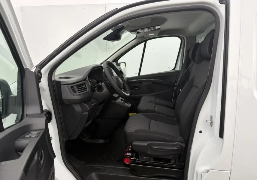 Vue intérieure côté conducteur du Renault Trafic Fourgon blanc glacier 2025, montrant les sièges avant et le tableau de bord.