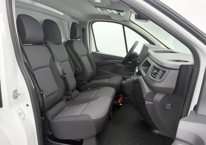 Vue intérieure côté conducteur du Renault Trafic Fourgon blanc Glacier, montrant la banquette passager et le tableau de bord gris.