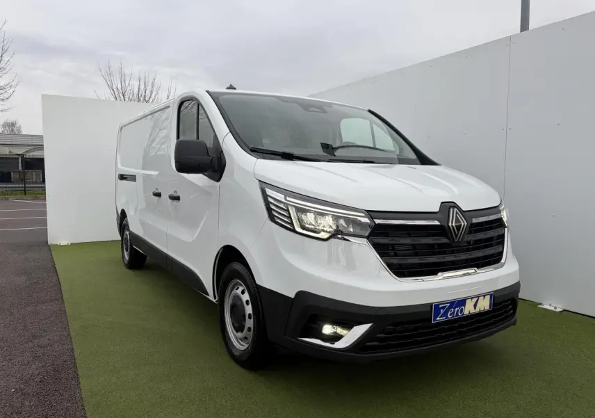Renault Trafic Fourgon blanc glacier vu en 3/4 avant droit, avec projecteurs LED allumés et jantes tôles.