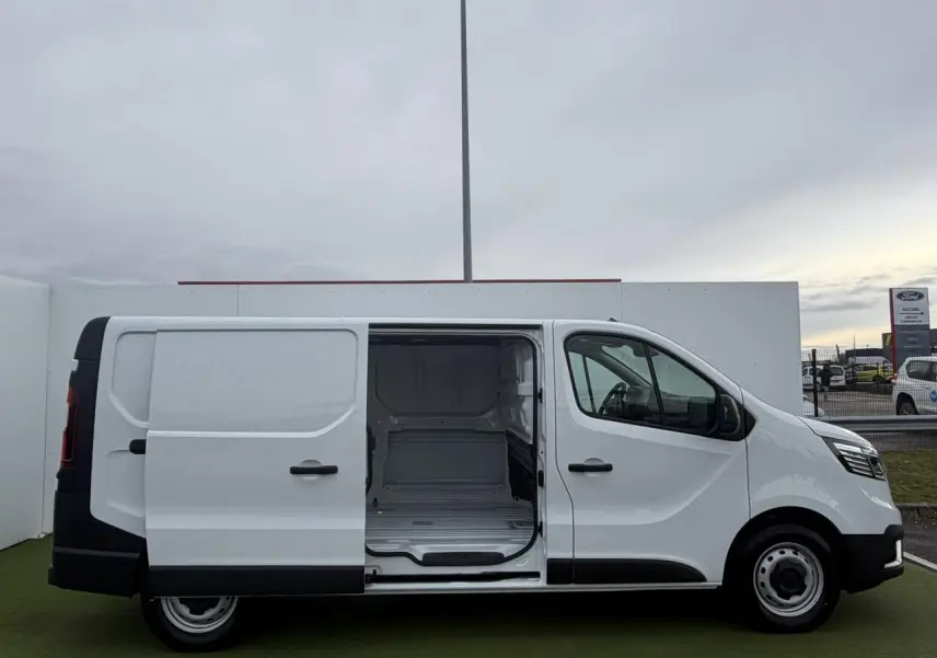 Vue latérale droite d’un Renault Trafic Fourgon blanc Glacier avec porte coulissante ouverte montrant l’espace de chargement vide.