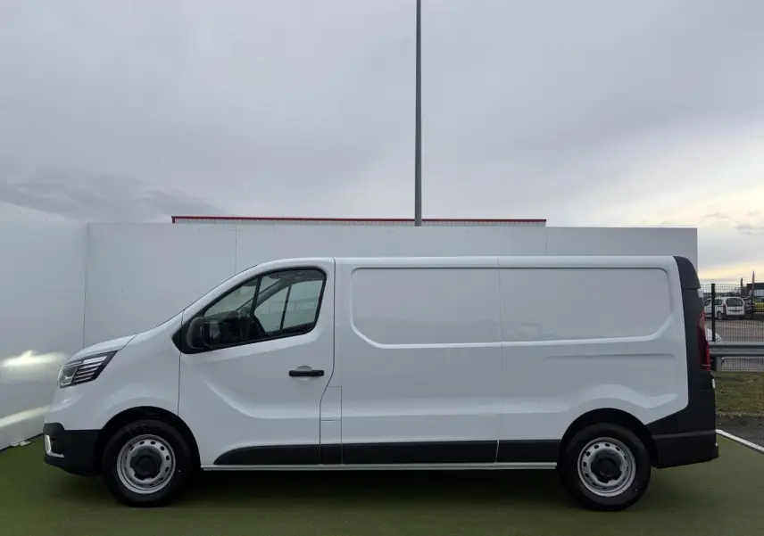 Profil droit d’un Renault Trafic Fourgon blanc glacier 2025 avec jantes tôles 16 pouces et porte latérale coulissante.