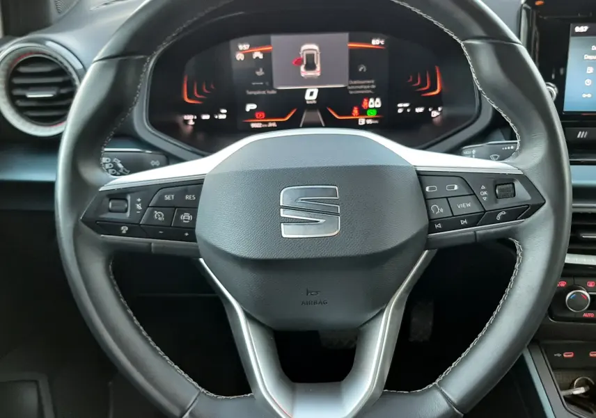 Vue rapprochée du volant noir de la SEAT Arona 2025 avec tableau de bord digital et commandes intégrées.