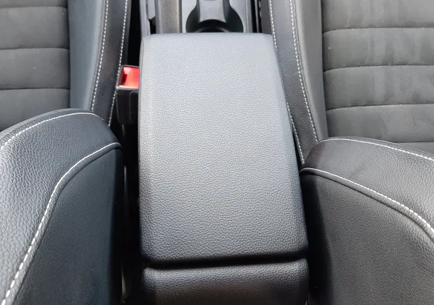 Gros plan sur l'accoudoir central en cuir noir avec surpiqûres blanches entre les sièges avant du SEAT Arona 2025.