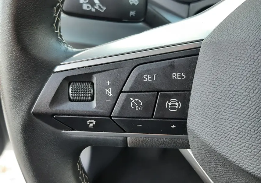 Gros plan sur les commandes au volant gauche du SEAT Arona 2025, finition X-PERIENCE, avec boutons de régulateur de vitesse et assistance.
